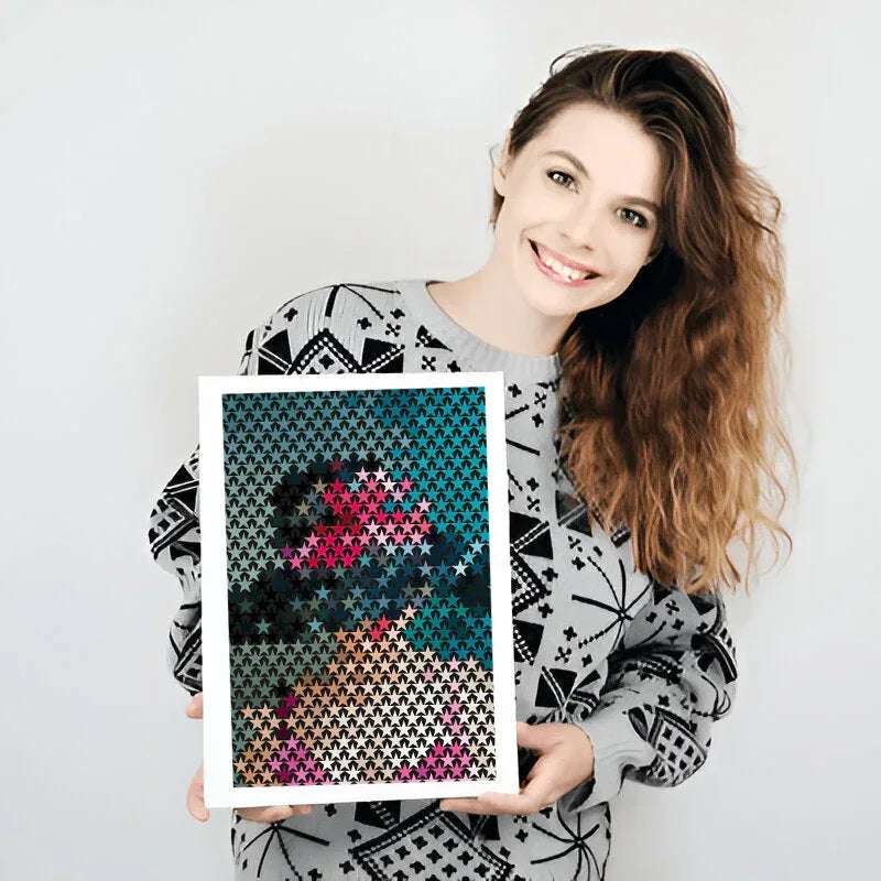 Woman holding a framed cross-stitch pattern against a white background