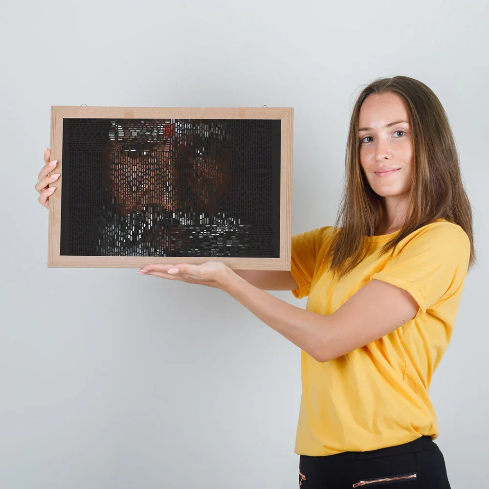 Woman holding a framed mosaic portrait against a plain background