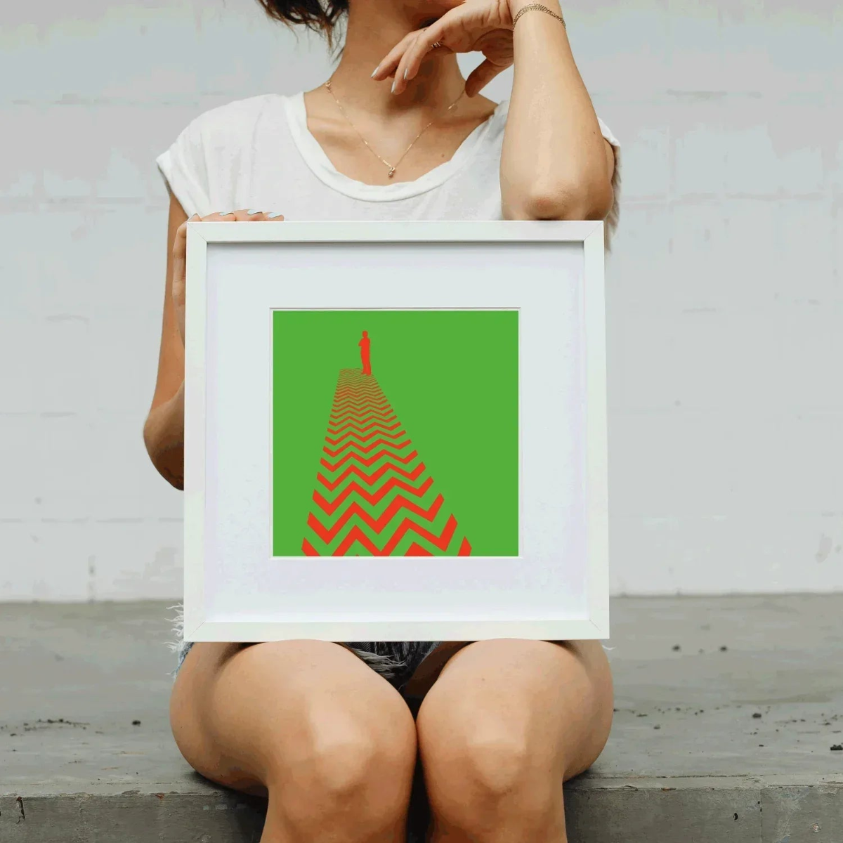 Person holding a framed artwork with a red and green design.