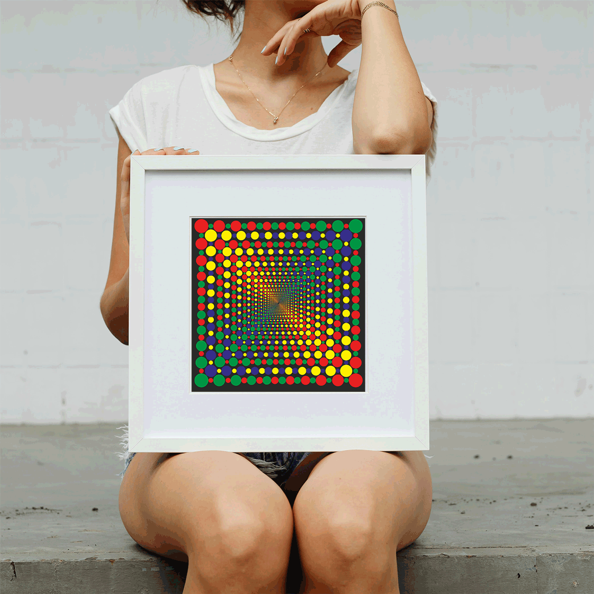 Person holding a framed colorful dot artwork against a light gray background