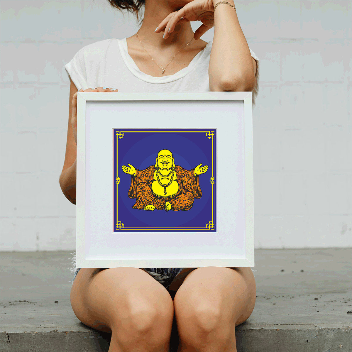 Person holding a framed artwork of a smiling Buddha on a plain background