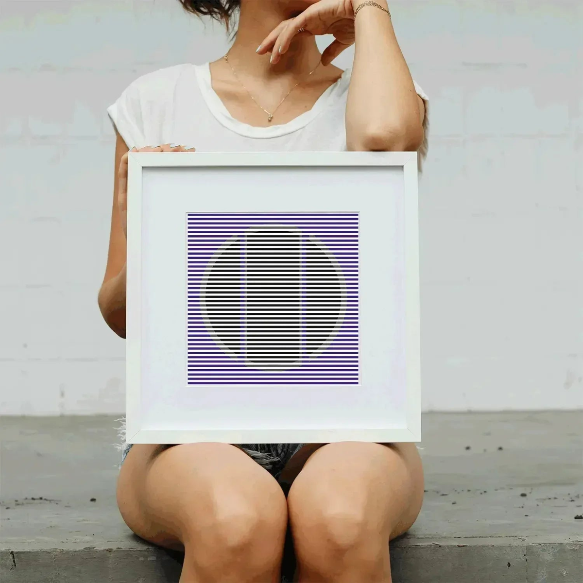 Person holding a framed abstract artwork with geometric design