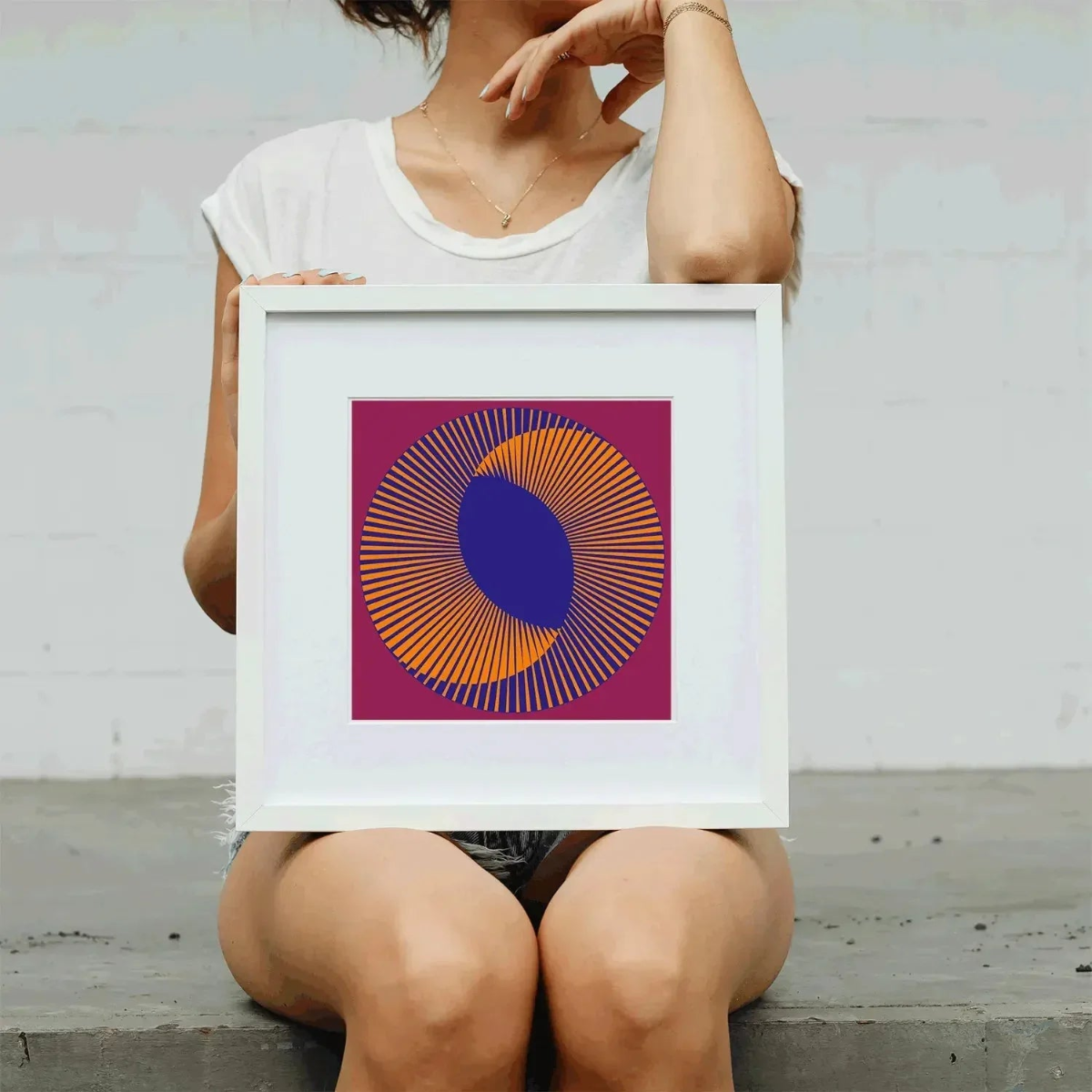 Person holding a framed abstract art piece with concentric circles.