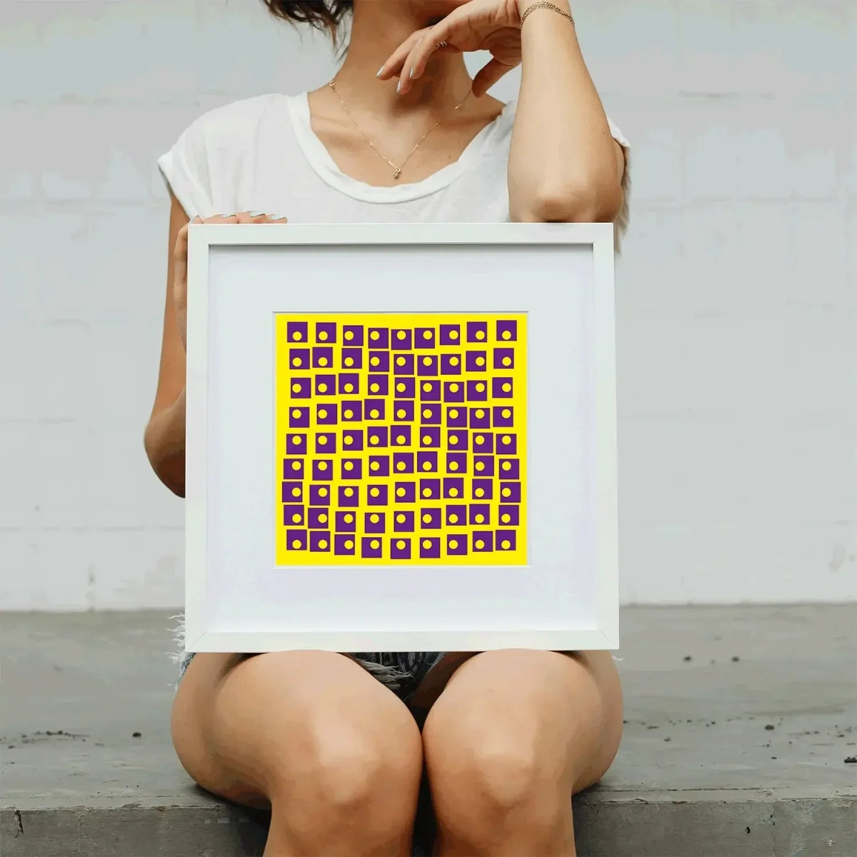 Person holding a framed artwork with a geometric pattern