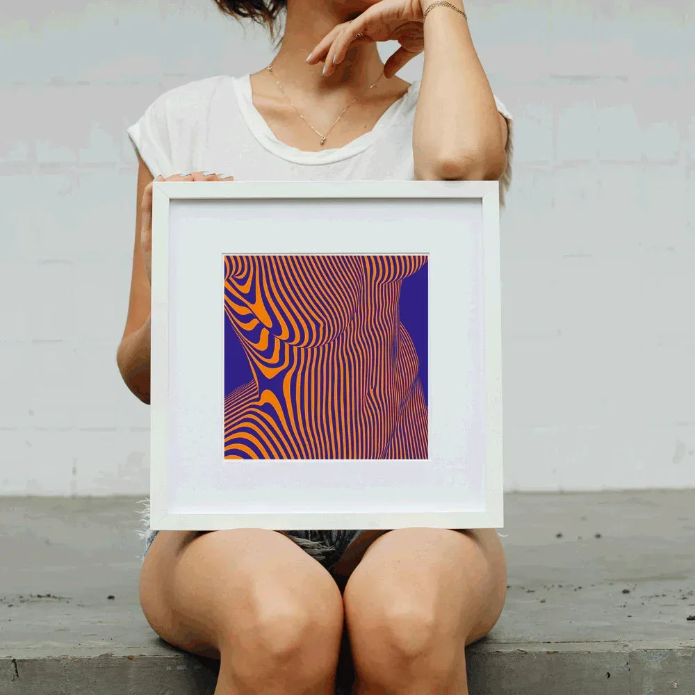 Person holding a framed abstract art print with wavy lines in orange and purple against a white background.