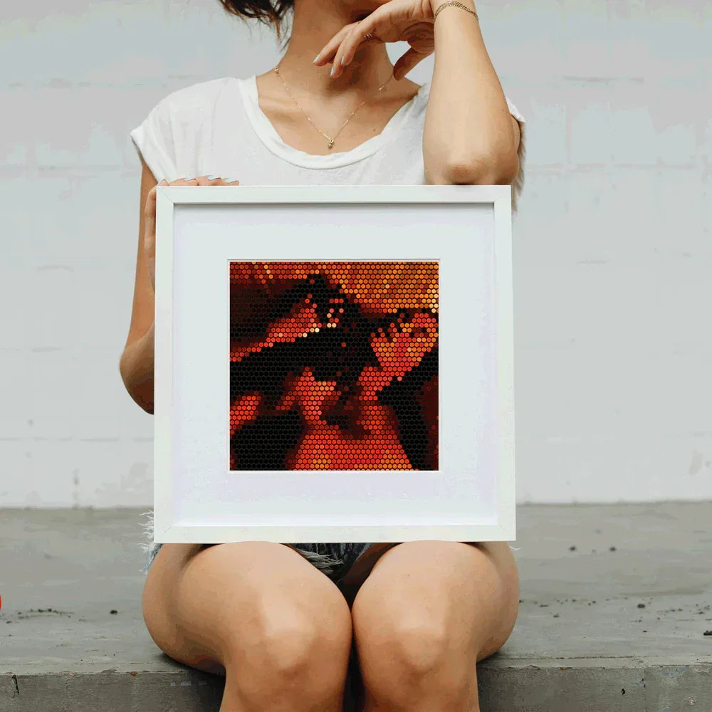 Person holding a framed mosaic art piece with abstract design