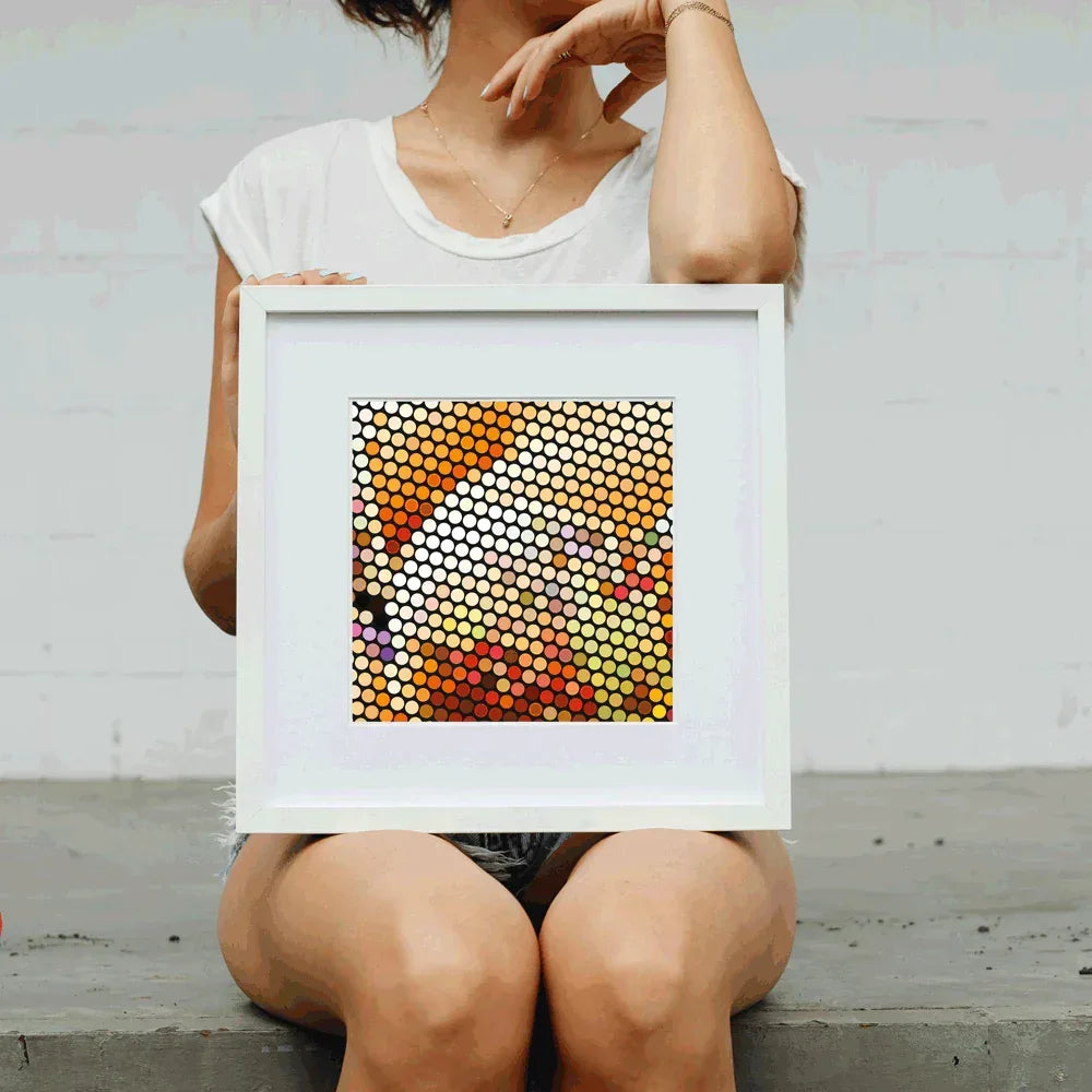 Person holding a framed abstract art piece with circular patterns.