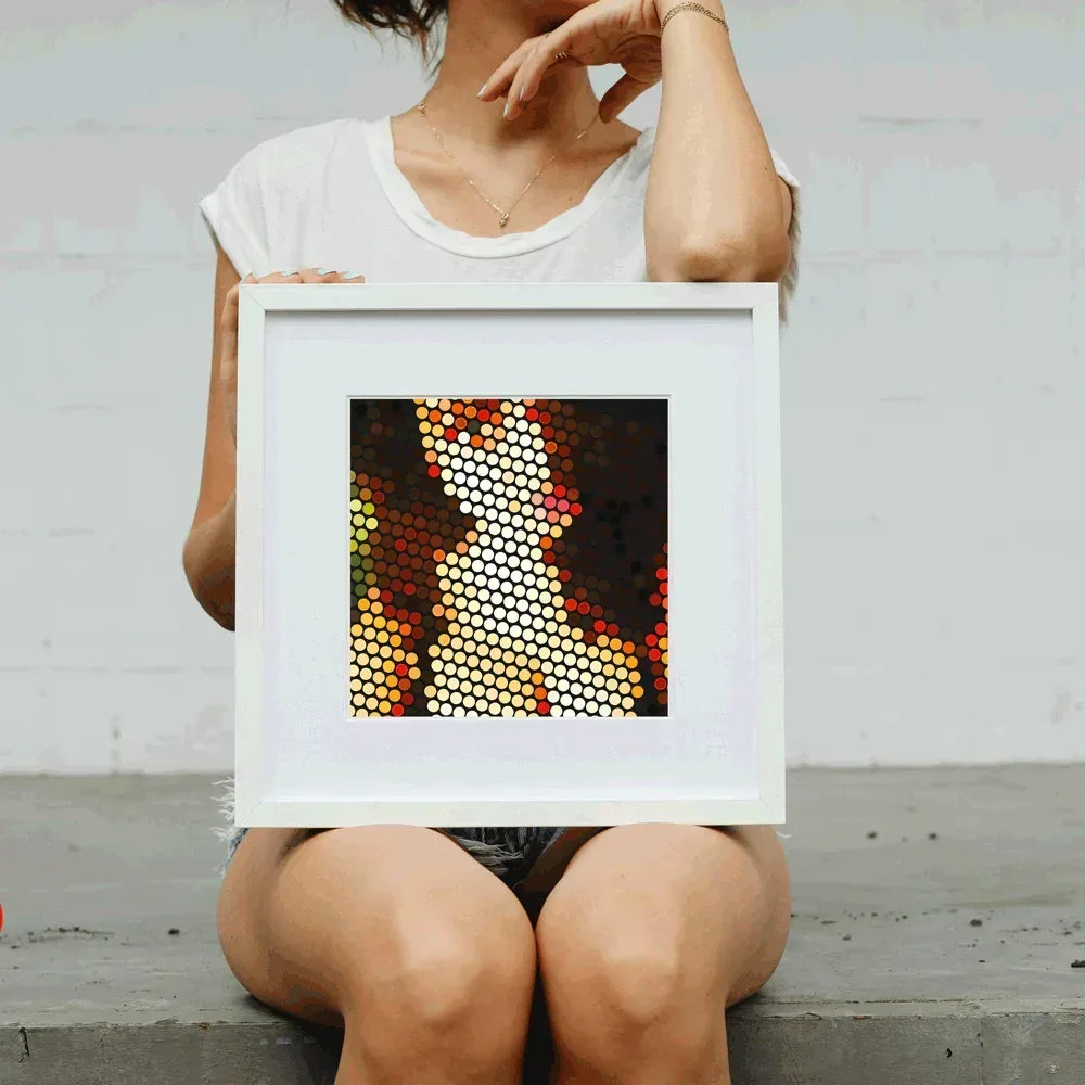 Person holding a framed abstract art piece with geometric patterns.
