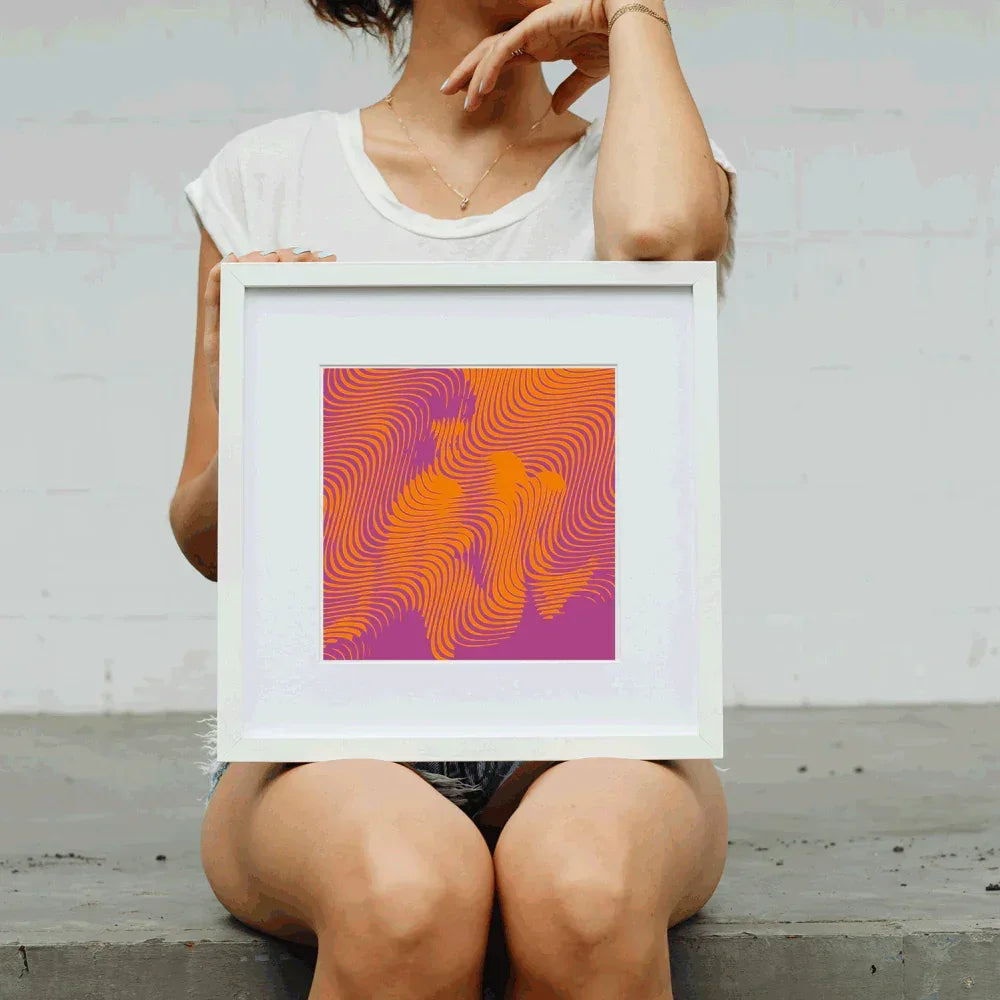 Person holding a framed abstract artwork with wavy patterns in orange and purple.