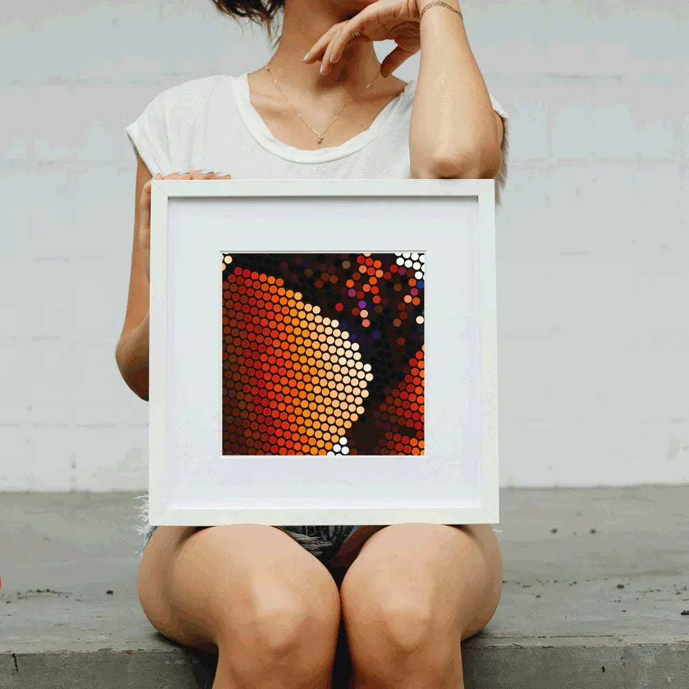 Person holding a framed abstract art piece with colorful hexagonal pattern.