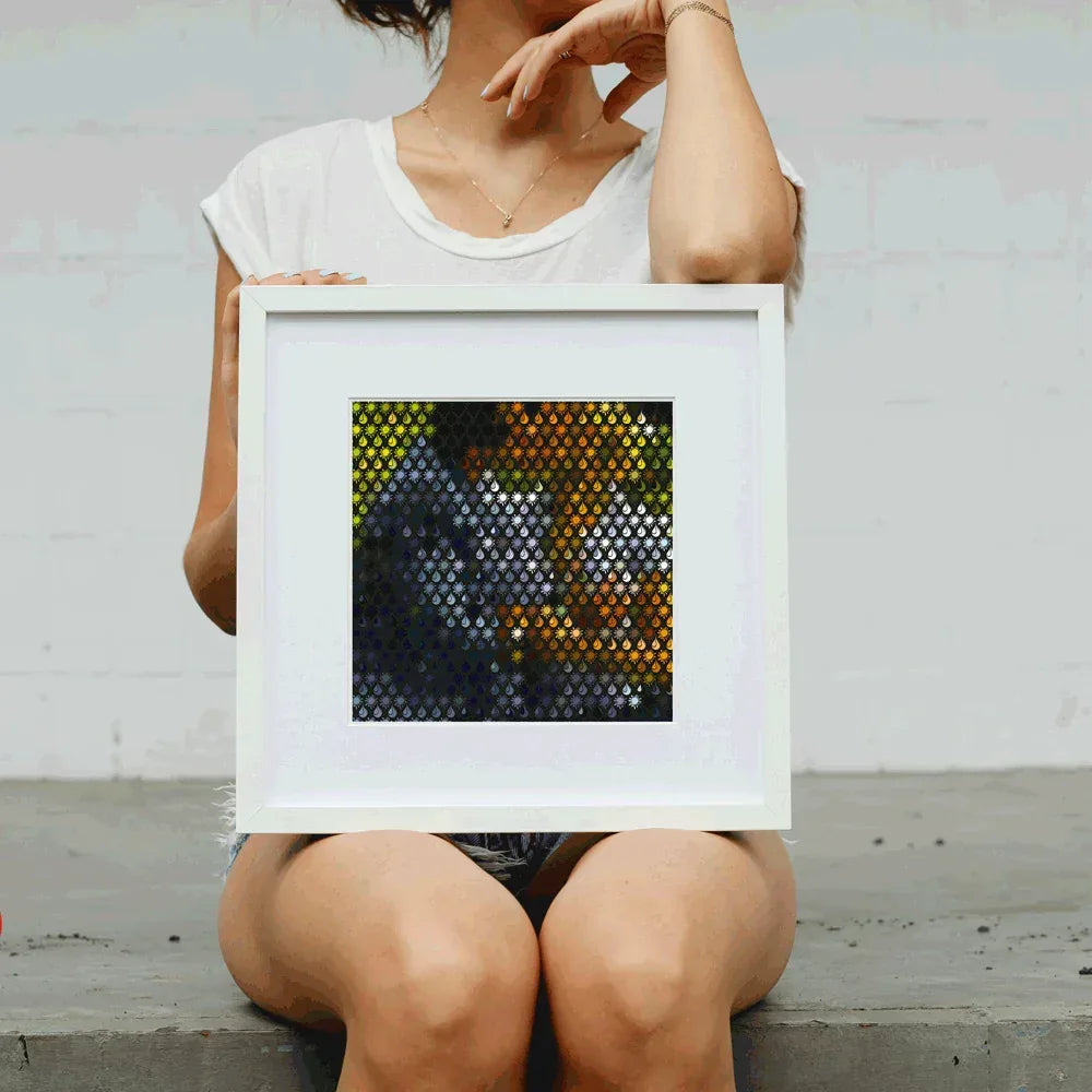 Person holding a framed mosaic art piece with geometric pattern