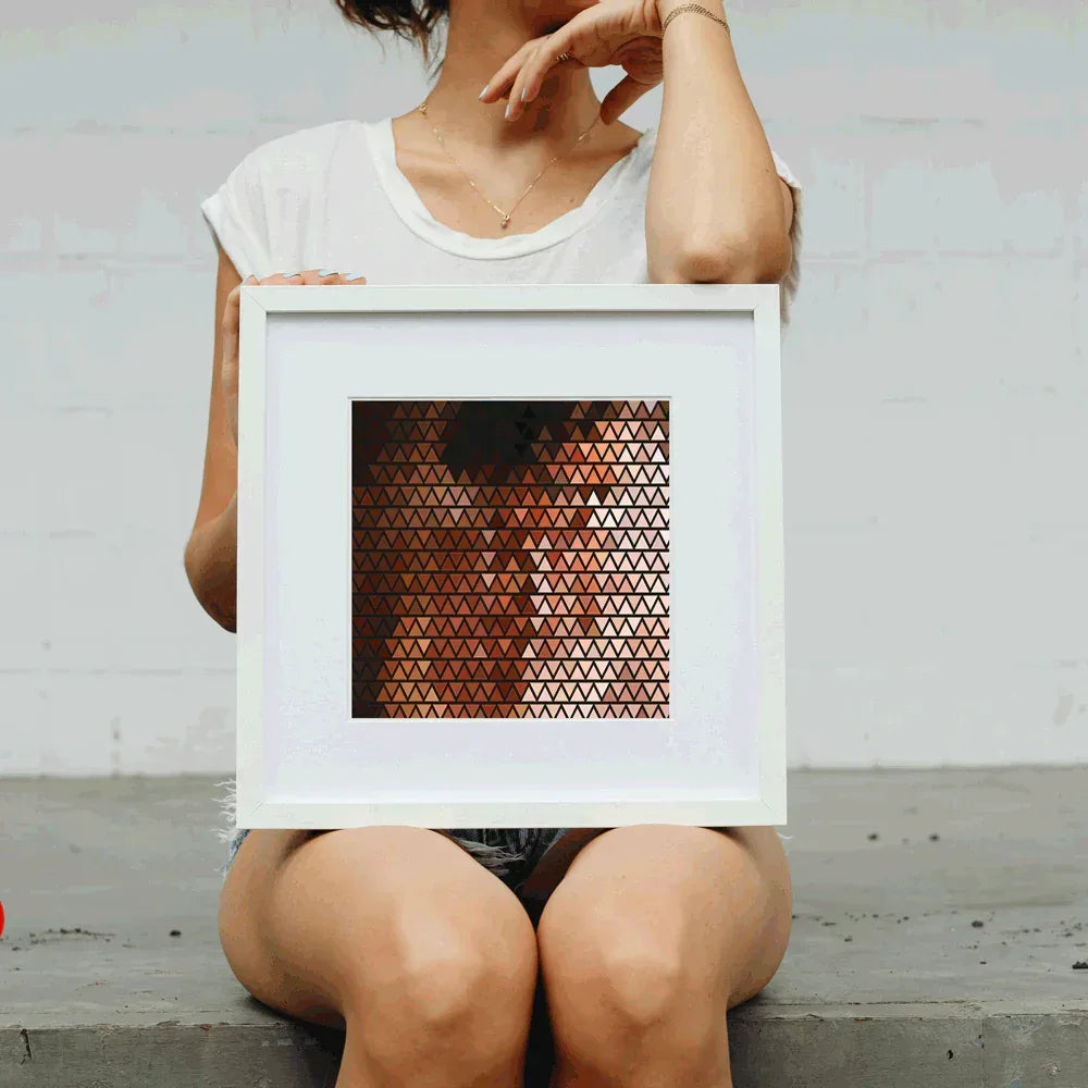 Person holding a framed geometric art piece with a white background