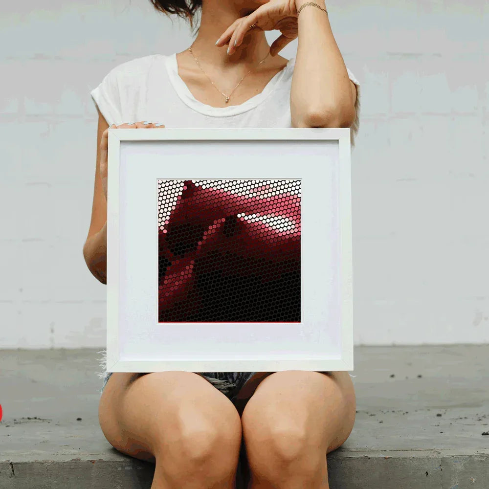Person holding a framed picture with a red and black abstract design against a light gray background