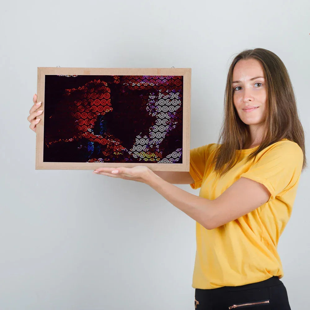 Woman holding a framed abstract artwork against a plain background