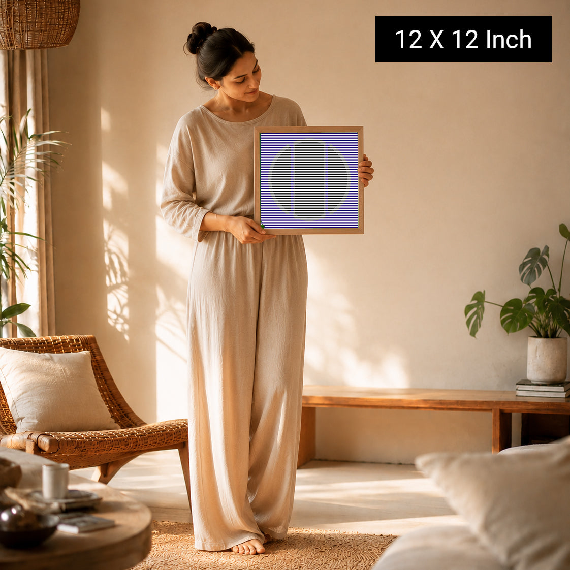A woman in a beige outfit holds a 12x12 inch therapeutic wall art print in a bright room with plants and natural light.