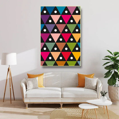Colorful geometric triangle pattern painting on a wall above a white sofa.