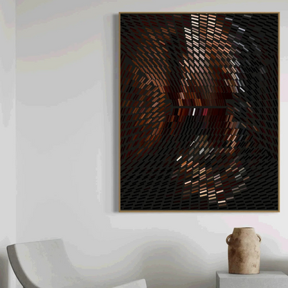 Abstract art piece in a gold frame on a white wall with a chair and vase in the foreground.