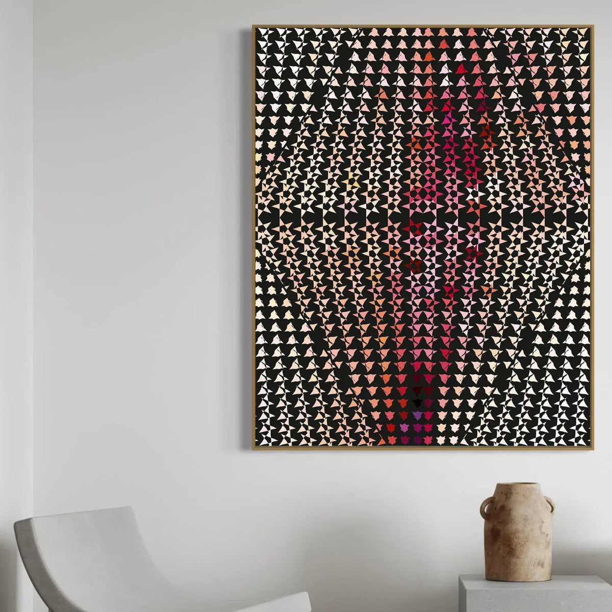 Abstract geometric art piece on a white wall with a chair and vase in the foreground.