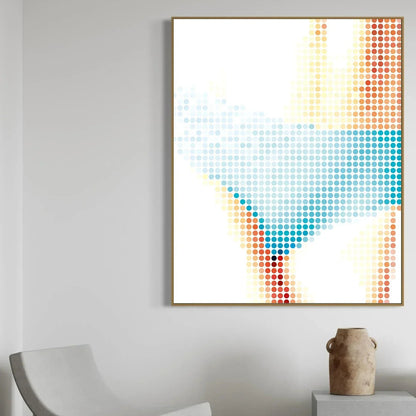 Abstract dot artwork in a gold frame on a gray wall with a chair and vase in the foreground.