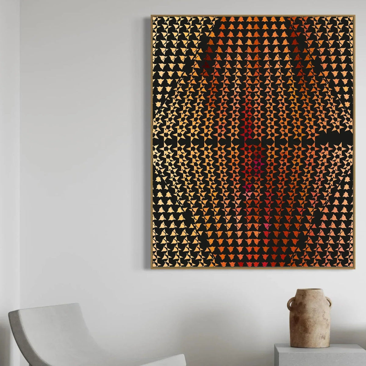 Abstract art piece with geometric pattern on a white wall, with a chair and vase in the foreground.