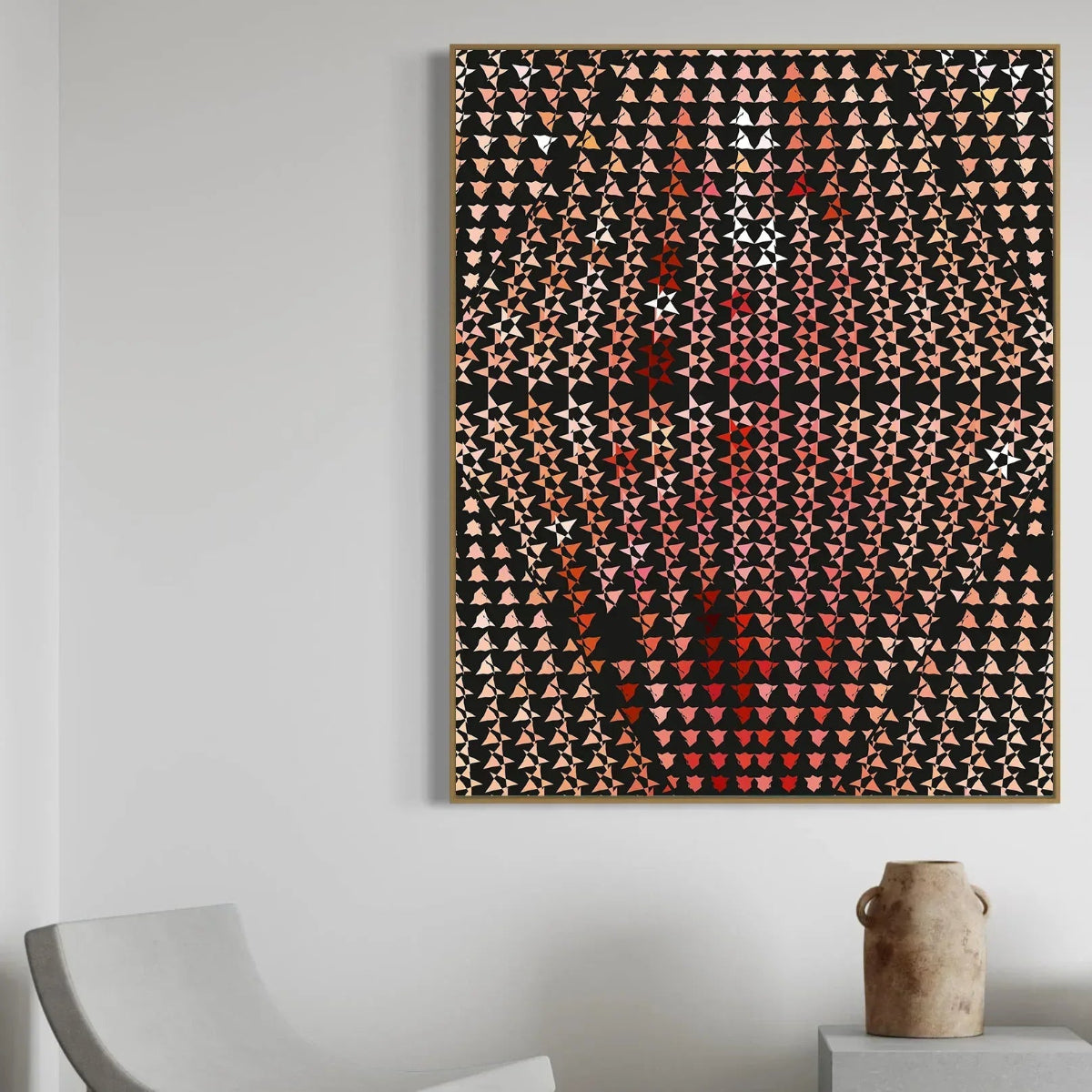 Abstract art piece with geometric pattern on a white wall above a chair and vase.