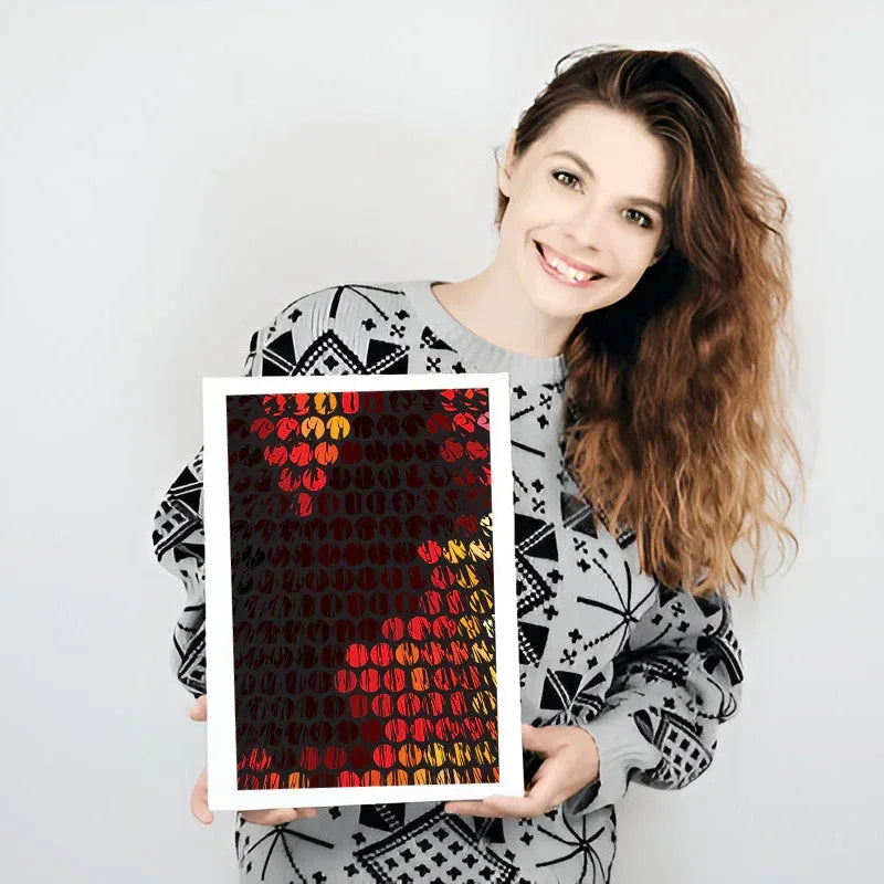 Woman holding a framed artwork with geometric patterns on a plain background