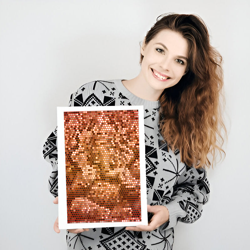 Woman holding a framed sequin art piece against a plain background