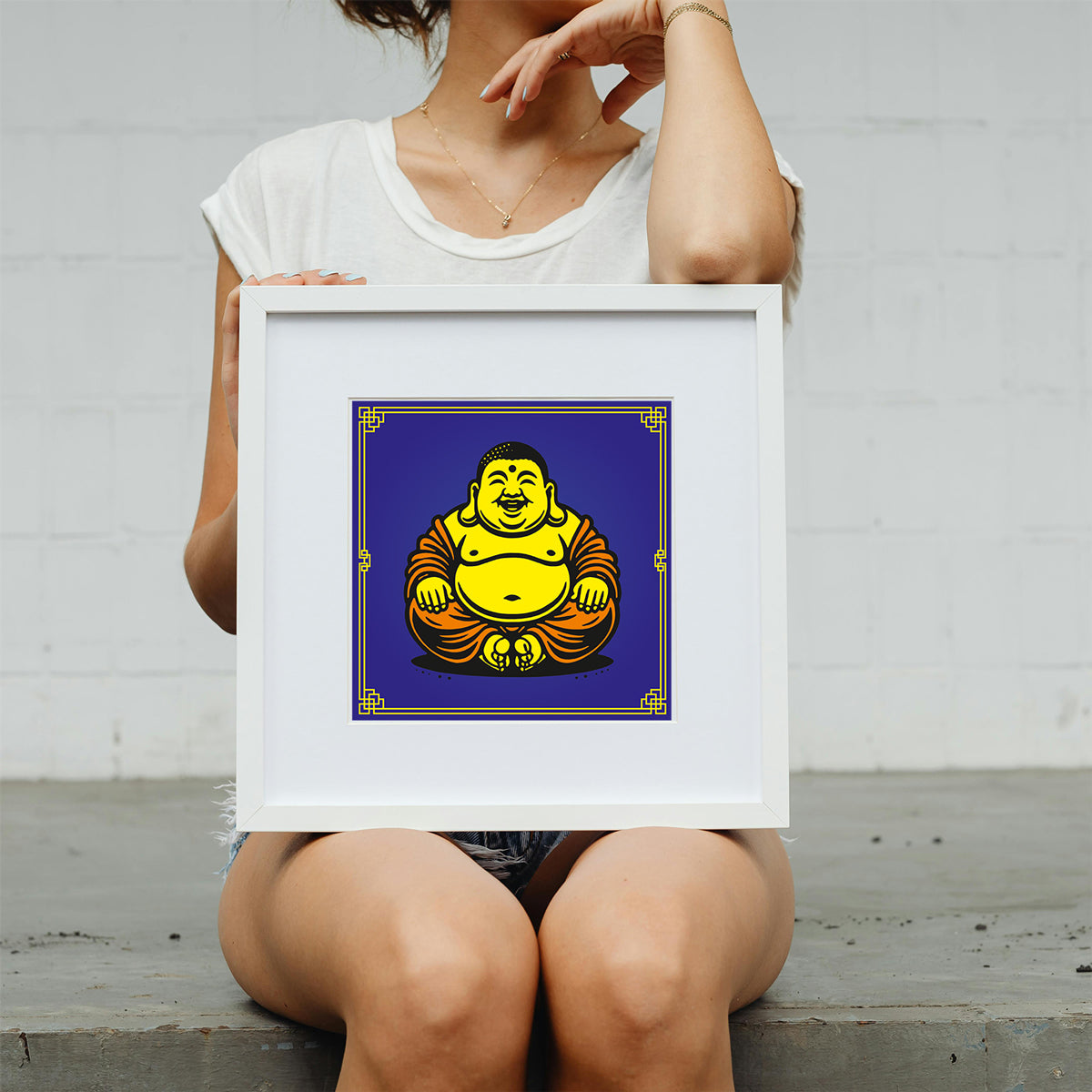 Person holding a framed artwork of a stylized Buddha figure on a white background