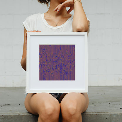 Person holding a framed abstract artwork with a purple and red pattern against a plain background