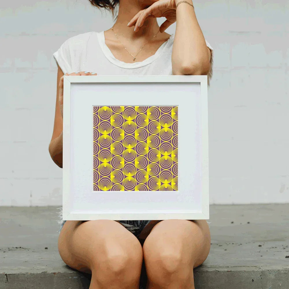 Person holding a framed artwork with a geometric pattern