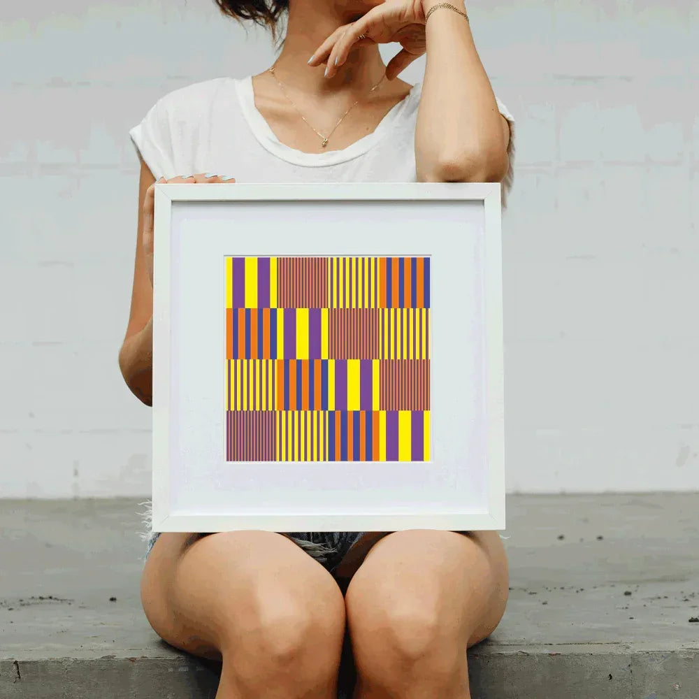 Person holding a framed colorful geometric art print against a plain background