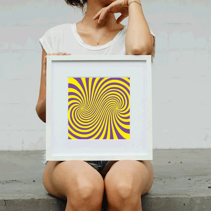 Person holding a framed yellow and purple spiral art print against a plain background