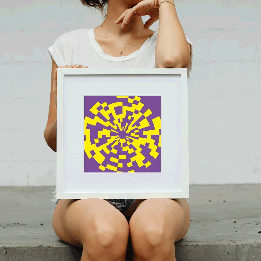 Person holding a framed purple and yellow abstract artwork against a plain background