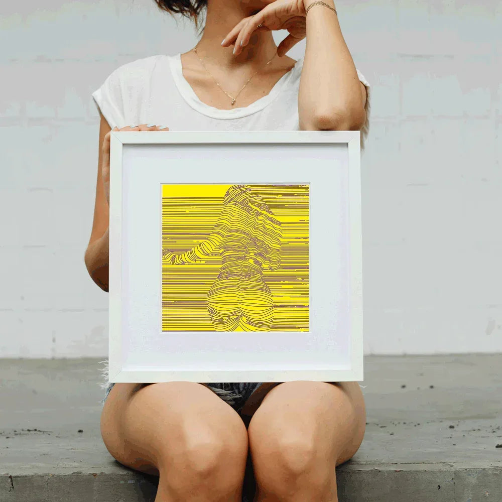 Person holding a framed yellow and white abstract art print against a plain background