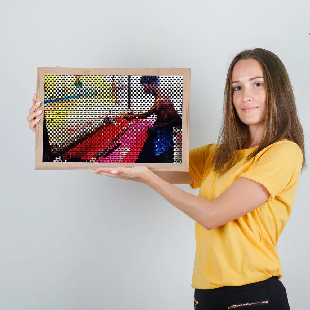 Woman holding a framed mosaic artwork of a dancer on a white background